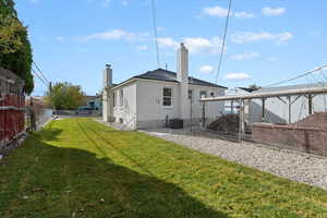 Back of property featuring a fenced backyard, a chimney, and brick siding