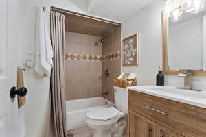 Bathroom featuring shower / bath combo, vanity, and a textured ceiling