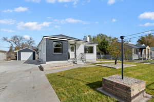 View of front of home featuring brick siding, an outbuilding, a chimney, concrete driveway, and a garage