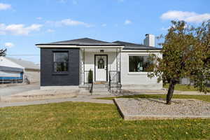 View of front facade with brick siding, a front yard, and a chimney