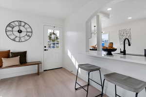 Entrance foyer featuring light wood-style floors, recessed lighting, and arched walkways
