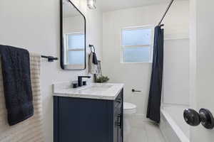 Full bath featuring vanity, light tile patterned flooring, and shower / bath combo with shower curtain