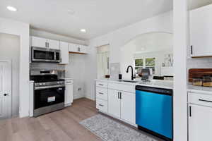 Kitchen featuring backsplash, appliances with stainless steel finishes, white cabinetry, and recessed lighting