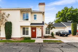 View of front facade featuring stucco siding, concrete driveway, roof with shingles, a chimney, and an attached garage
