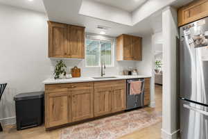 Kitchen with appliances with stainless steel finishes, brown cabinets, and light wood-style flooring
