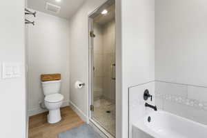 Bathroom with a shower stall, light wood finished floors, and a garden tub