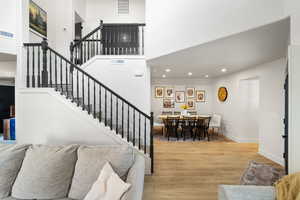 Stairway featuring wood finished floors, recessed lighting, and a towering ceiling