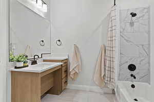 Full bathroom with vanity, shower / bath combo with shower curtain, and light tile patterned flooring