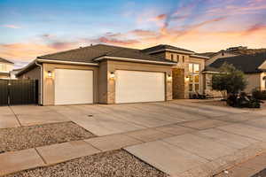 View of front facade featuring a garage, concrete driveway, stucco and stone siding