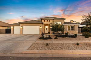 Prairie-style house featuring stone siding, an attached garage, concrete driveway, stucco siding, and a chimney