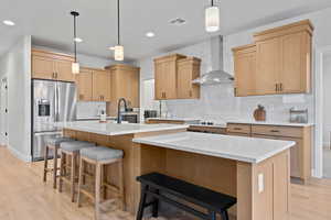 Kitchen with hanging light fixtures, light wood finished floors, decorative backsplash, light brown cabinets, and recessed lighting