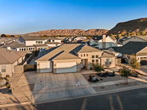 View of front facade featuring a residential view, a garage, driveway, stone siding, and a mountain view