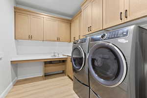 Laundry room featuring light wood-style flooring, washing machine and dryer, and cabinet space