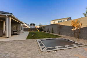 Fenced backyard featuring a patio and a playground