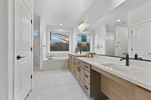 Full bath featuring double vanity, a garden tub, light tile patterned floors, a marble finish shower, and recessed lighting