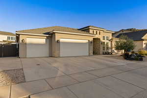 Prairie-style house featuring stone siding, driveway, a garage, stucco siding, and a gate