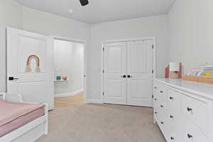 Bedroom with light colored carpet, a closet, and ceiling fan