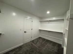 Walk in closet featuring dark colored carpet