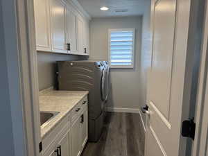 Washroom featuring dark wood-style floors, cabinet space, separate washer and dryer, and recessed lighting