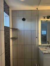 Full bathroom featuring vanity, a tile shower, and a textured ceiling