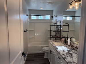 Bathroom featuring vanity, shower / bathtub combination, dark wood-style flooring, and a textured ceiling