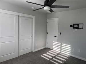 Unfurnished bedroom with a closet, carpet, ceiling fan, and a textured ceiling