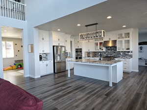 Kitchen featuring stainless steel appliances, white cabinetry, decorative backsplash, light granite countertops, and recessed lighting