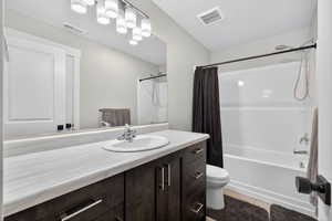 Full bath with shower / tub combo with curtain, vanity, and light tile floors