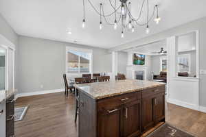 Kitchen featuring a kitchen breakfast bar, light stone counters, dark wood-style flooring, and a semi-formal dining space