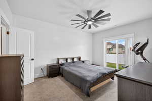 Primary bedroom with light carpet, access to exterior, and a ceiling fan
