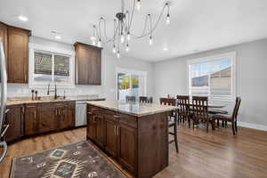 Kitchen with a center island, a breakfast bar, light wood finished floors, light stone counters, and recessed lighting