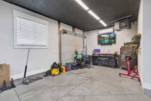 Workshop space in garage featuring side roll-up door, furnace, and mini split system