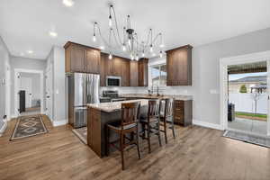 Kitchen with dark wood cabinets, light stone counters, stainless steel appliances, a kitchen bar, and a center island