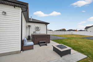 Fenced backyard with a hot tub, a patio area, and a fire pit
