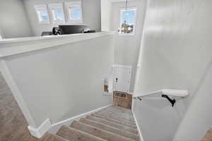 Stairs with carpet flooring, a high ceiling, and a chandelier