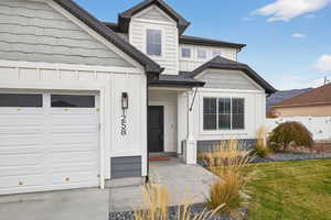 View of front of property with board and batten siding, roof with shingles, and a garage