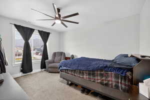 Bedroom featuring light carpet large window and a ceiling fan