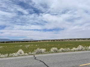 View of asphalt street featuring a view of rural / pastoral area and a mountain view