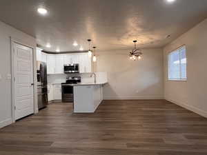 Kitchen with a peninsula, light countertops, stainless steel appliances, white cabinets, and decorative backsplash