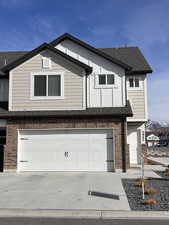 View of front facade featuring a shingled roof, brick siding, driveway, and a garage