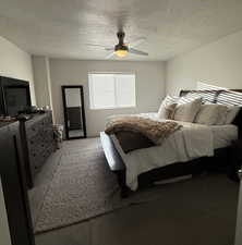 Carpeted bedroom featuring a textured ceiling and ceiling fan