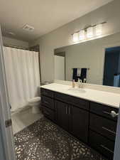 Full bath featuring a textured ceiling, curtained shower, vanity, and light tile patterned floors