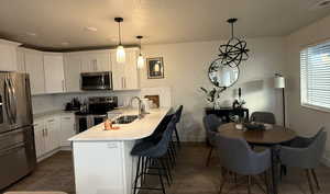 Kitchen featuring stainless steel appliances, a peninsula, tasteful backsplash, white cabinetry, and a textured ceiling