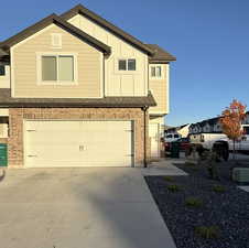 View of front facade with brick siding, concrete driveway, a garage, board and batten siding, and a shingled roof