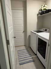 Washroom featuring light tile patterned floors and washing machine and clothes dryer