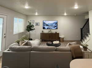 Living area featuring a textured ceiling, stairs, and wood finished floors
