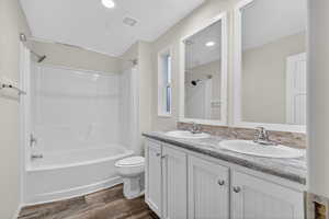 Full bath featuring washtub / shower combination, double vanity, dark wood-style flooring, and recessed lighting