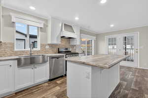 Kitchen with crown molding, white cabinets, decorative backsplash, a kitchen island, and dark wood finished floors