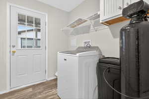 Laundry room with cabinet space, wood finished floors, and washing machine and clothes dryer