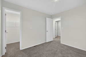 Unfurnished bedroom featuring a walk in closet and carpet